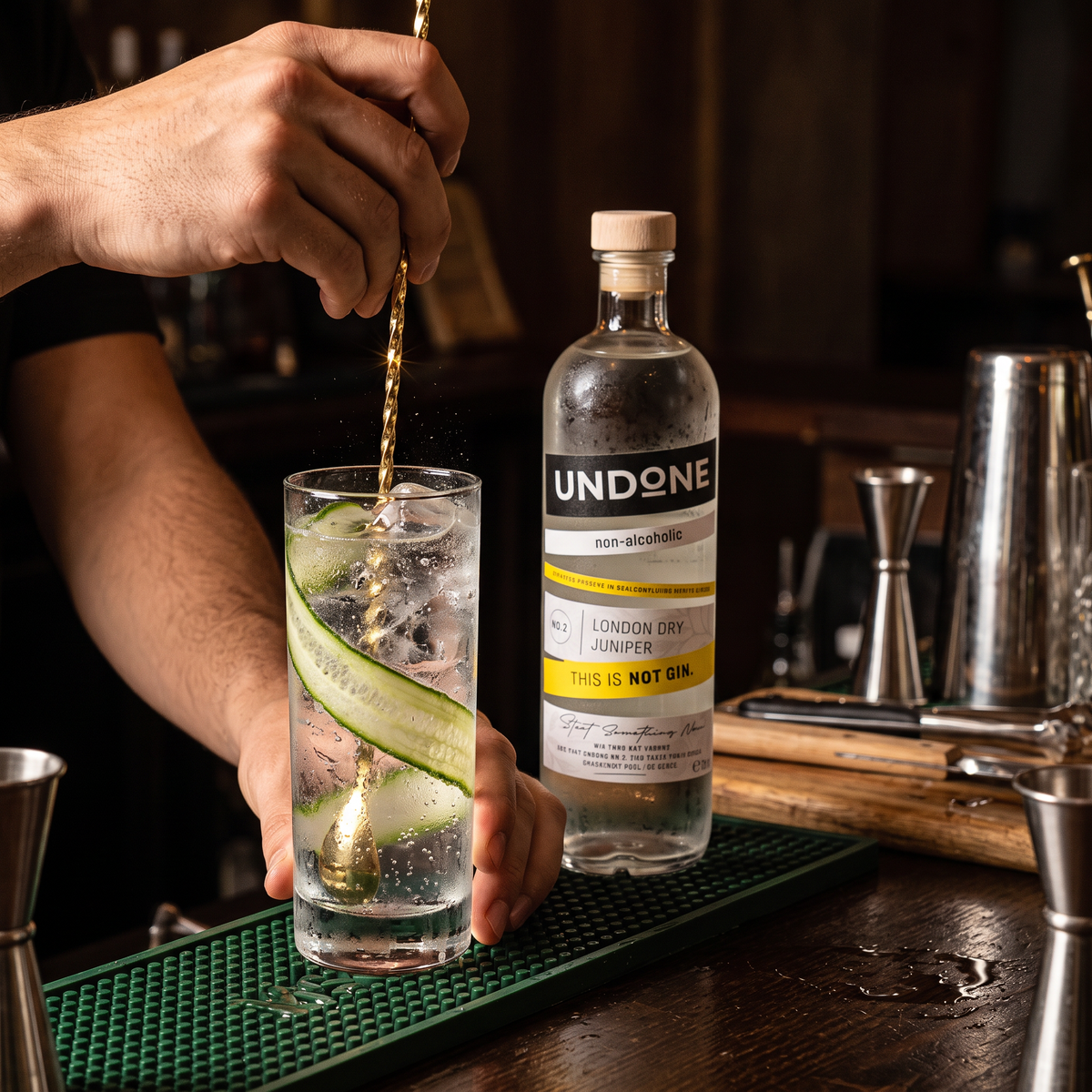 Bartender stirring a NOT GIN and Tonic with cucumber beside the UNDONE No. 2 NOT GIN bottle